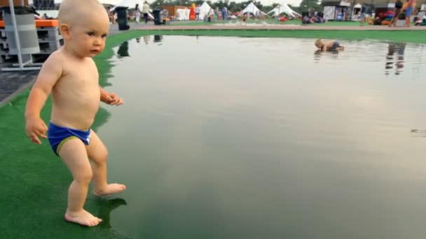 Un bambino cammina a piedi nudi attraverso una pozzanghera — Video Stock