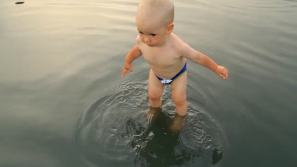 Un enfant marche à travers une flaque — Video