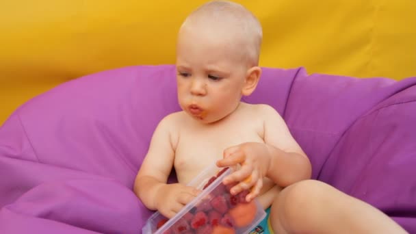 Criança comendo frutas deitada em uma cadeira fácil — Vídeo de Stock