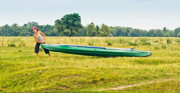 Girl pulling a canoe across the field — Stock Photo, Image