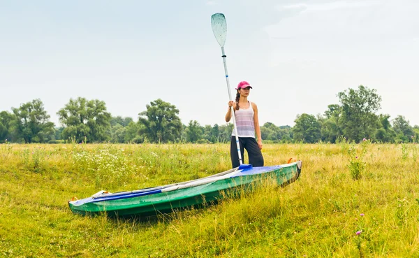Girl pulling a canoe across the field — Stock Photo, Image