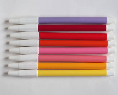 Masada mor, pembe ve sarı keçeli kalemler var.