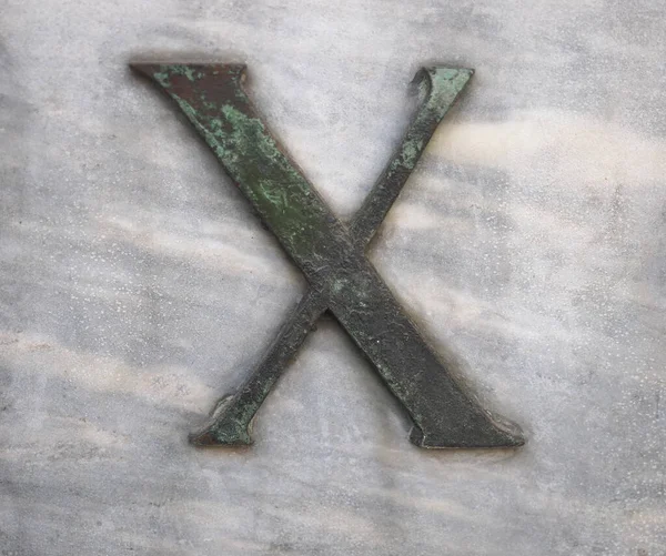 大理石の背景に青銅で鋳造された大文字X — ストック写真