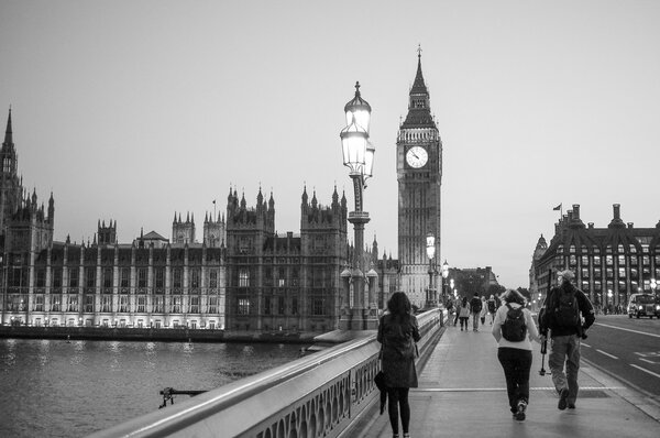 LONDON, UK - JUNE 10, 2015: People crossing Westminster Bridge over River Thames with Houses of Parliament and Big Ben in the background at night in black and white