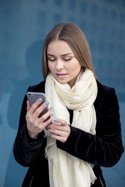 Executive werkt met een mobiele telefoon in de straat met kantoorgebouwen op de achtergrond — Stockfoto