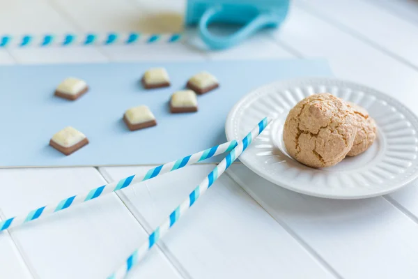 Biscotti su un piatto bianco e pezzi di cioccolato su sfondo bianco blu — Foto Stock