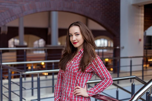 Jovem mulher bonita encaracolado em camisa xadrez e jeans posando e sorrindo — Fotografia de Stock