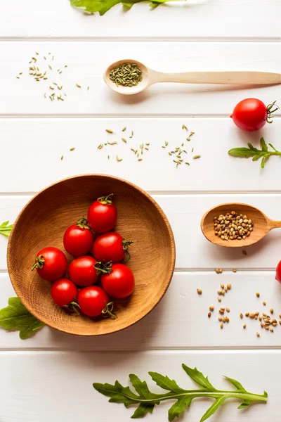 Ingredience pro rajčatovou omáčkou (cherry rajčata, čerstvé bylinky, česnek, paprika) na bílém pozadí dřevěná. Potraviny nebo vaření koncepce, pohled shora. — Stock fotografie