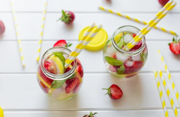 Dos vasos con tubos de cóctel. limonada de fresa casera, servida con fresas frescas, menta, lima y cubitos de hielo — Foto de Stock