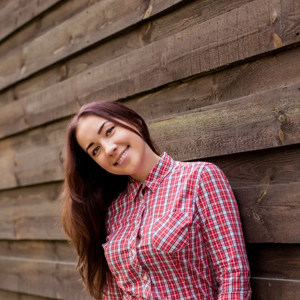 Linda morena hipster sorrindo contra pranchas de madeira — Fotografia de Stock