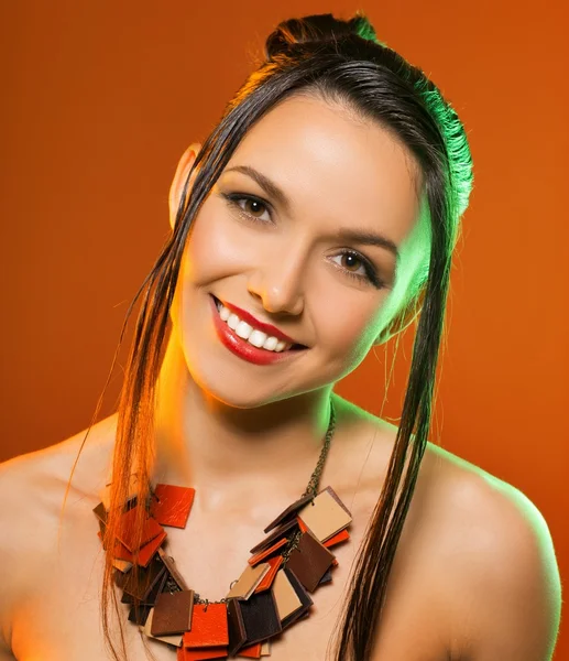 Menina bonito com decoração em um pescoço. estúdio fundo laranja — Fotografia de Stock