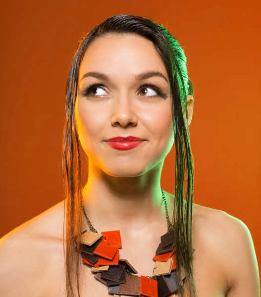 Linda chica con decoración en un cuello. estudio naranja fondo —  Fotos de Stock