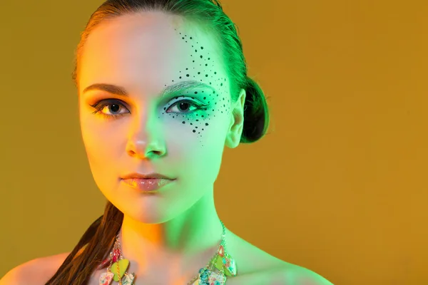 Aantrekkelijke jonge vrouw met creatieve make-up. foto werd genomen in een studio op een gele achtergrond — Stockfoto