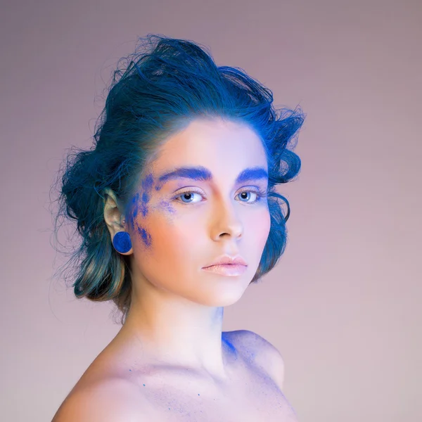 Красива жінка з креативним яскравим макіяжем над синім — стокове фото