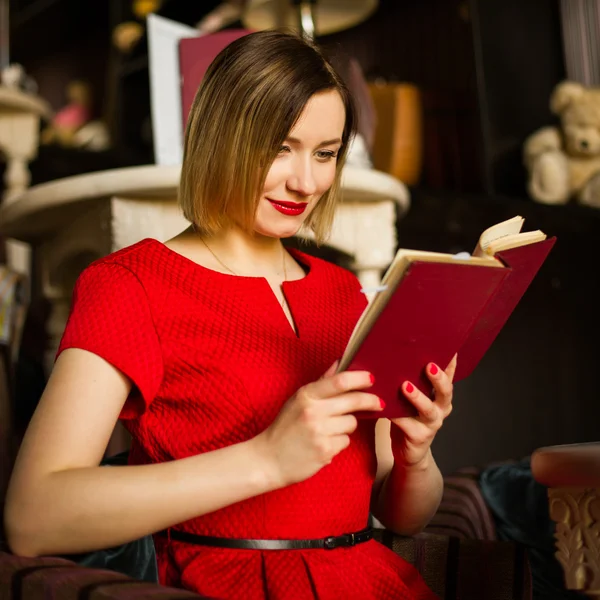 红色的口红，坐在餐厅里，读一本小说的女人 — 图库照片