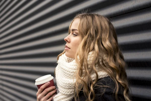 Блондинка с кофе на черном полосатом фоне — стоковое фото