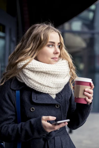 Portret van vrouw texting op rechterborst. Lachende meisje houdt van een smartphone en schrijven. Gelukkig jonge vrouw stond aan koffie bar Stockfoto