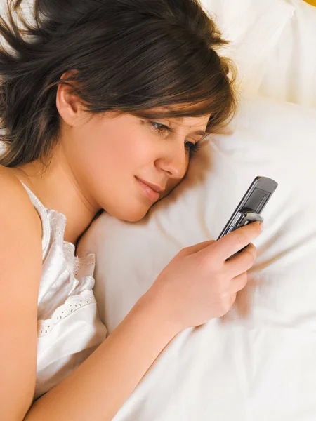 Frau liest SMS im Bett — Stockfoto