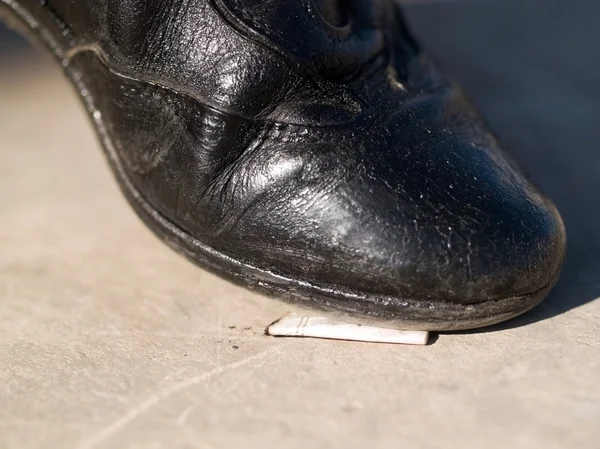 Cigarette butt under shoe — Stock Photo, Image