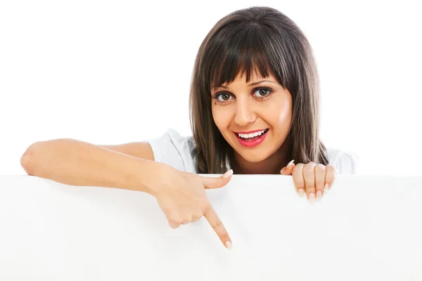 Young woman pointing behind billboard — Stock Photo, Image