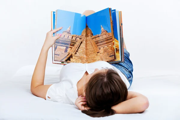 Молодая женщина читает журнал о путешествиях — стоковое фото