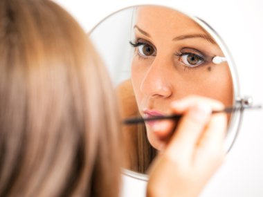 Makyaj yapan genç bir kadın.