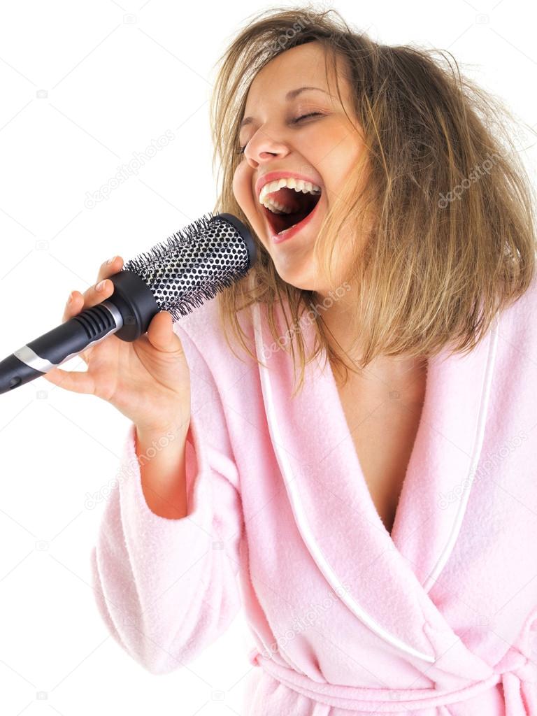 Woman in housecoat singing with hairbrush