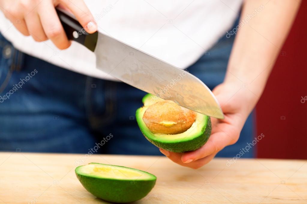 Young woman peeling avocado