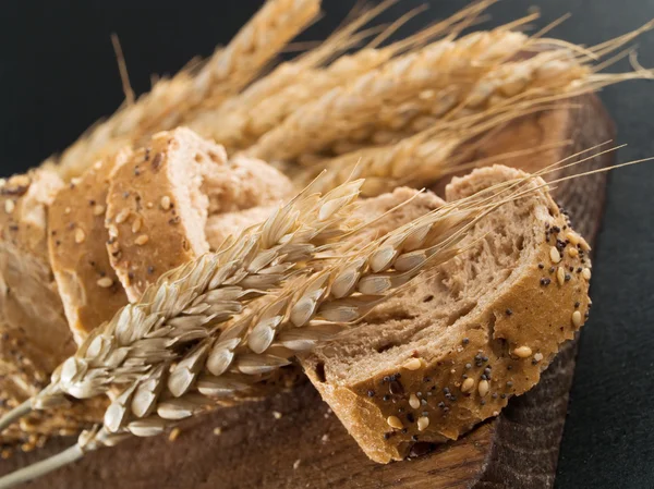 Slices of fresh baked bread and wheat — Stock Photo, Image