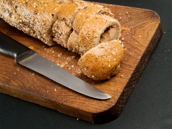 Pan sobre tabla de madera con cuchillo — Foto de Stock
