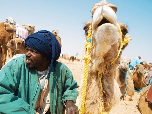 Velho tunisiano em pé junto ao seu camelo — Fotografia de Stock
