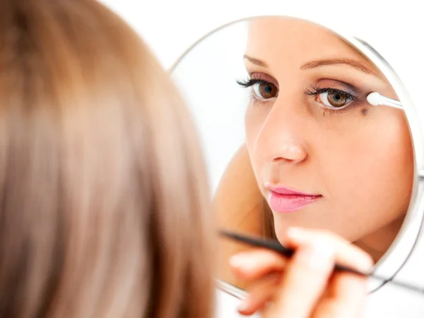 Tillämpar make-up på ung kvinna ansikte Stockfoto
