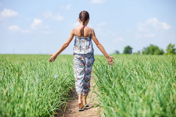 Dívka chůze přes pole — Stock fotografie