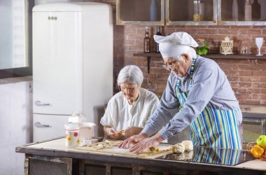 Kıdemli çift evde mutfakta hamur işleri hazırlıyor. Adam şef şapkası takıyor..