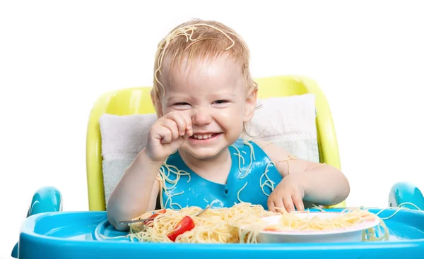 Malý chlapec jíst špagety s těstovinami na hlavě — Stock fotografie