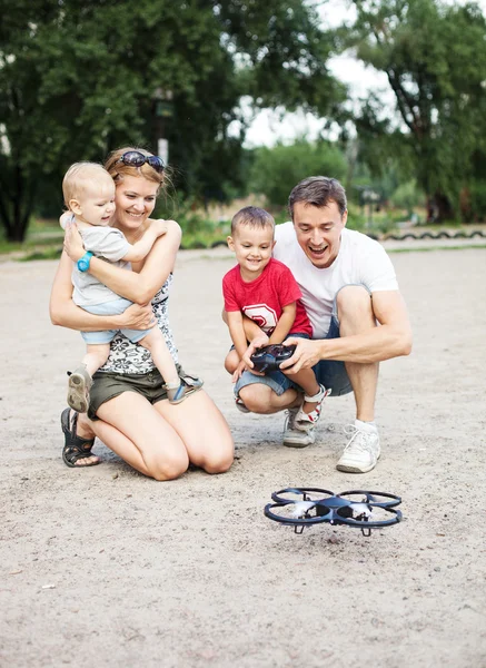 Família jovem com dois meninos brincando com RC quadrocopter brinquedo — Fotografia de Stock