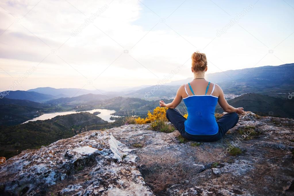 Young woman sitting on a rock and enjoying valley view