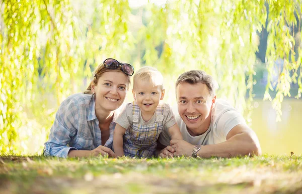Šťastní rodiče s chlapcem batole. Matka, otec a syn relaxační na trávníku. — Stock fotografie