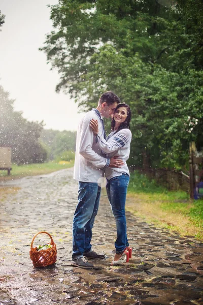 Young couple in Ukrainian style clothes kissing under rain — Stock Photo, Image