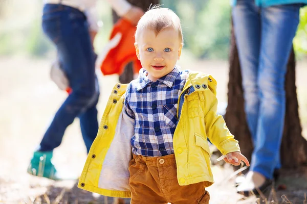 Хлопчик Тоддлер в яскравий осінній день, з розмитими дорослими на задньому плані — стокове фото