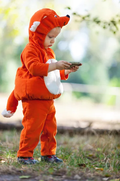 Niño en traje de zorro sosteniendo teléfono inteligente —  Fotos de Stock
