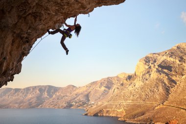 Kadın dağcı üzerinde overhanging cliff, Kalymnos Island, Yunanistan