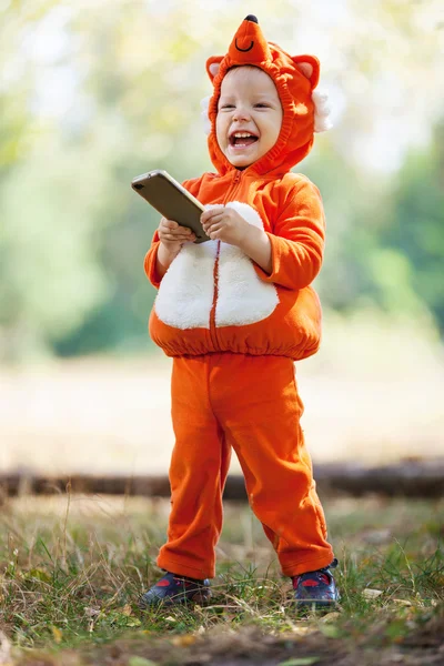 Fröhlicher Kleinkind Junge im Fuchskostüm hält Smartphone in der Hand — Stockfoto