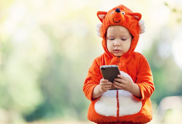 Småbarn pojke i fox kostym håller smartphone — Stockfoto