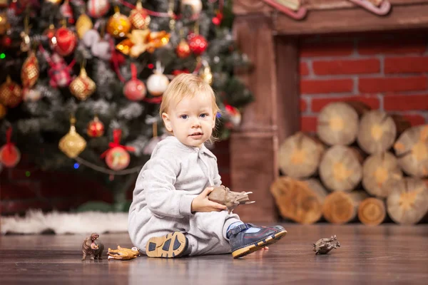 Menino alegre brincando com seus animais de brinquedo na árvore de Natal — Fotografia de Stock