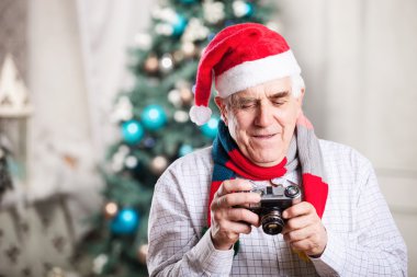 Retro tarzı kamera görüntüsünü seyir ve Noel arka planı gülümseyen kıdemli adam