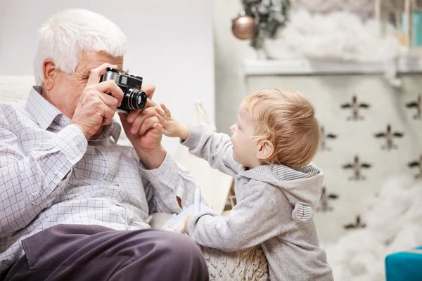 Hombre mayor tomando fotos de su nieto en Navidad — Foto de Stock
