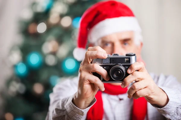 Senior man taking photo on Christmas background — Stock Photo, Image