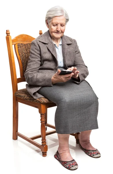 高级的女人坐在椅子上时使用移动电话 — 图库照片