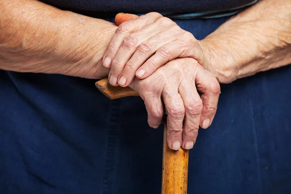 Closeup of senior woman's hands on wooden walking stick — Stock Photo, Image